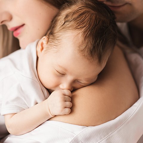 Symbolbild junger Eltern mit Baby auf dem Arm