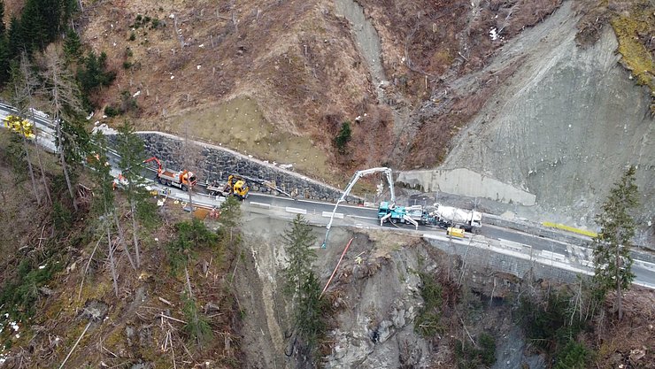 © Land Tirol Vier LKWs arbeiten an einer Landstraße, da darunter ein Hang abgerutscht ist.