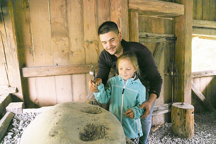 Papa mit Tochter beim Steineklopfen